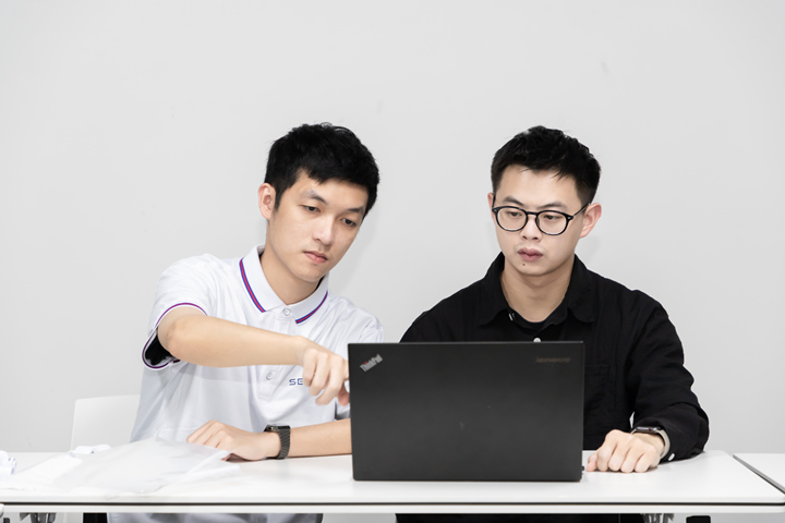 Two staff members are in front of the computer planning the products process for customers.