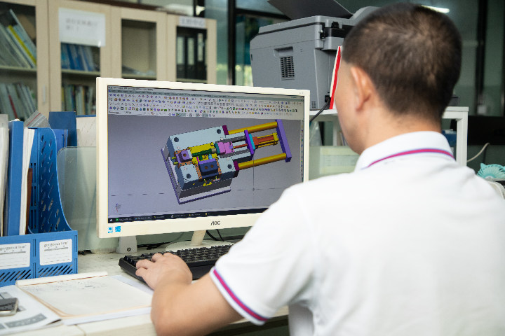 A mold designer designs a precision injection mold on computer software.