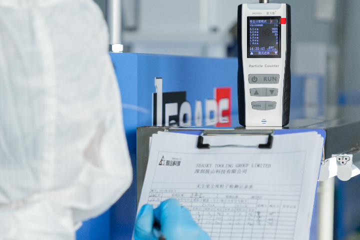 A staff member takes a cleanliness meter in the cleanroom and records the measurements.