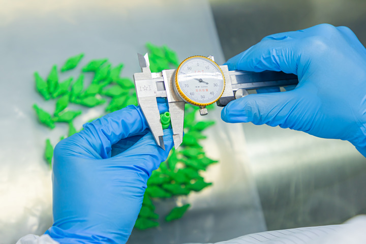 A staff member is measuring a injection molded product with a measuring tape.