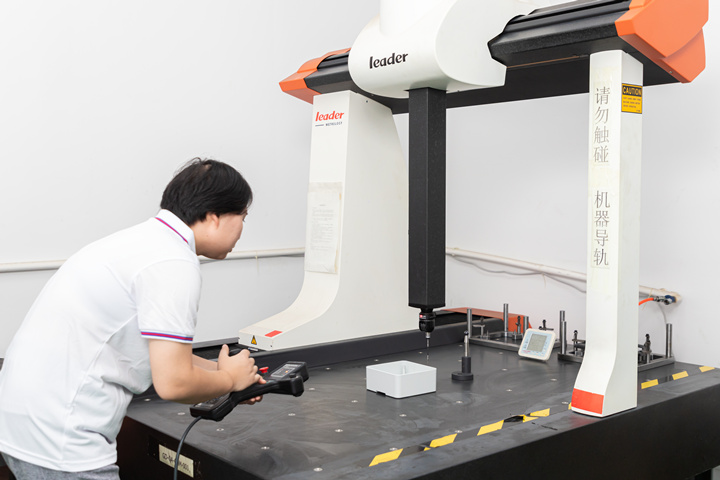 A quality inspector uses a Coordinate Measuring Machine to inspect injection molded products.